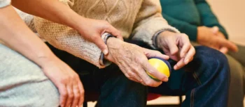 aide soignante tenant la main d'une personne plus agée
