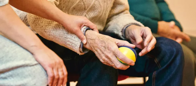 aide soignante tenant la main d'une personne plus agée