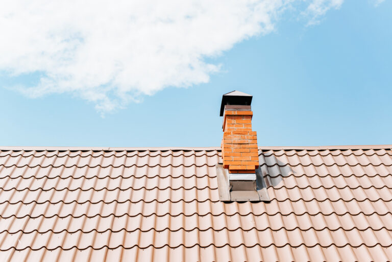 Toiture en tuiles d’une maison avec cheminée en briques, illustrant l’amortissement de la toiture et des composants d’un bien immobilier en location meublée LMNP